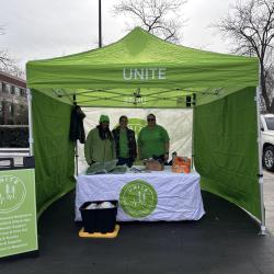 three people under a pop-up canopy tent handing out cold weather supplies