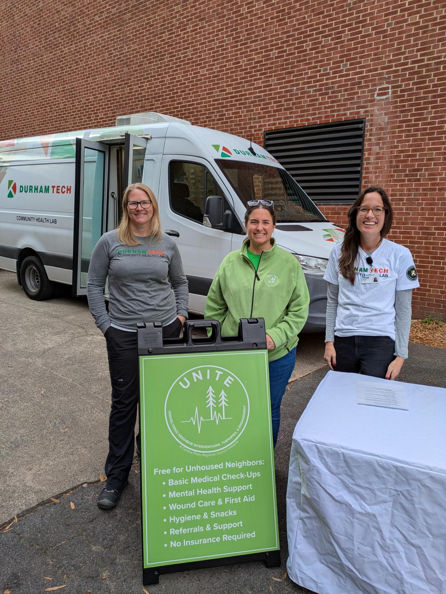 medical van with three people standing in front of it and a sign showing what is offered